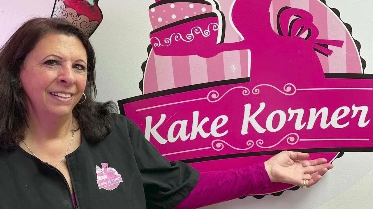 Woman posing with the Kake Korner sign